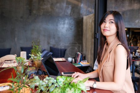 Photo for Young woman using laptop working online in restaurant - Royalty Free Image