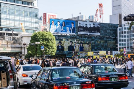 Foto de TOKIO, JAPÓN - 24 DE OCTUBRE DE 2016: Taxi clásico en el distrito comercial de Shibuya con multitud de personas - Imagen libre de derechos