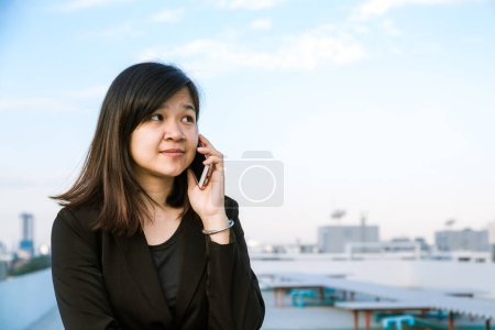 Photo for Happy Asian Businesswoman talking on smart phone with building background. - Royalty Free Image