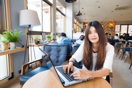 Foto de Sonriendo asiática estudiante mujer casual navegación el internet en café - Imagen libre de derechos