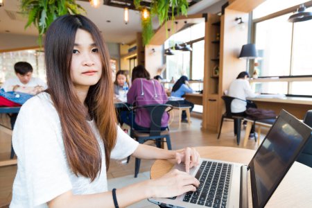 Foto de Sonriendo asiática estudiante mujer casual navegación el internet en café - Imagen libre de derechos