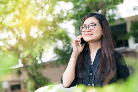 Foto de Feliz asiático gafas mujer uso a hablar en inteligente teléfono al aire libre, comunicación de la naturaleza - Imagen libre de derechos