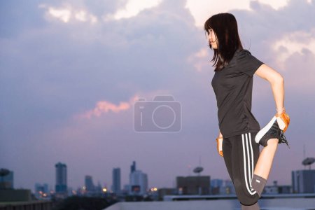 Photo for Asian female in sports clothing make body stretching before workout on building background. - Royalty Free Image