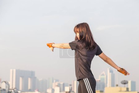 Photo for Asian woman fitness sunrise stretch before jogging workout wellness concept building background. - Royalty Free Image