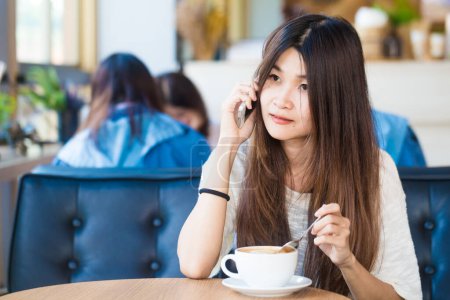 Téléchargez les photos : Femmes asiatiques assis dans la bibliothèque avec une tasse de café pour faire une idée de démarrage d'entreprise fond avec la foule - en image libre de droit