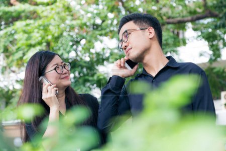 Téléchargez les photos : Homme d'affaires et femme utilisent le téléphone portable pour parler affaires dans le parc, Co entreprise - en image libre de droit