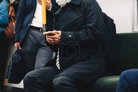 Téléchargez les photos : Business japanes homme main utiliser smartphonwe assis dans JR ville train main gros plan - en image libre de droit