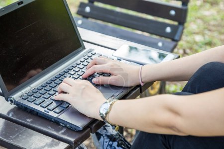 Téléchargez les photos : Souriant entreprise asiatique femme assis dans le parc public extérieur utilisation ordinateur portable en ligne de travail - en image libre de droit