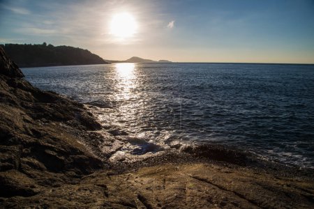 Foto de Salpicaduras de olas marinas en la playa rocosa día soleado mañana amanecer mar de Andamán - Imagen libre de derechos