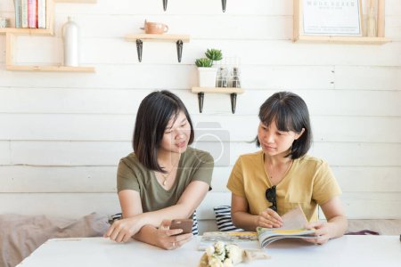 Foto de Feliz asiático mujer amigo sentado en café orden algunos beber buscando en menú relación concepto - Imagen libre de derechos