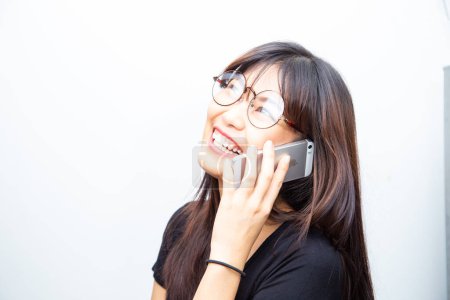Photo for Cheerful business asian woman in casual shirt talking on smartphone on white background - Royalty Free Image