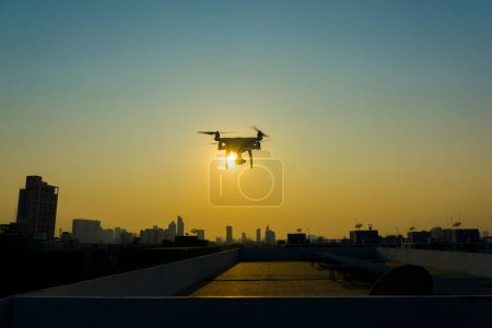 Foto de Silueta quadcopter volando en el edificio de la ciudad puesta de sol - Imagen libre de derechos