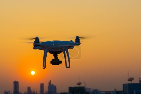 Foto de Silueta quadcopter volando en el edificio de la ciudad puesta de sol - Imagen libre de derechos