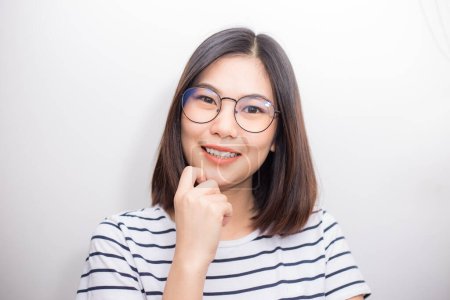 Foto de Bastante asiático las mujeres con camisa y gafas sonriendo en blanco fondo - Imagen libre de derechos
