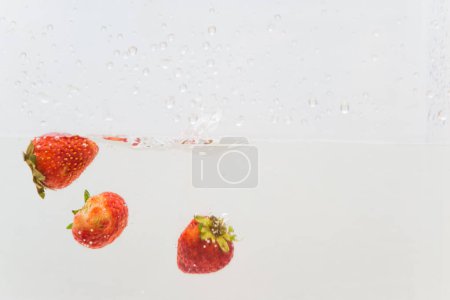 Foto de Salpicadura de fruta de vitamina fresa en agua sobre fondo blanco - Imagen libre de derechos