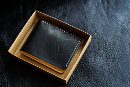 Téléchargez les photos : Portefeuille en cuir tanné végétal sur fond cuir noir, objet artisanal - en image libre de droit