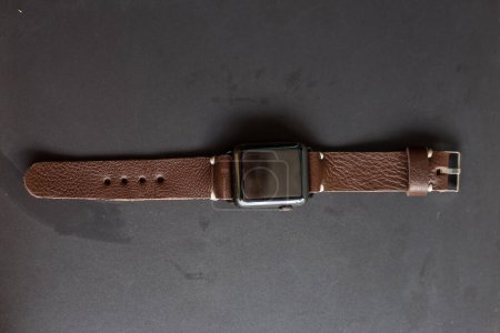 Téléchargez les photos : Bracelet en cuir véritable avec montre intelligente sur fond noir - en image libre de droit