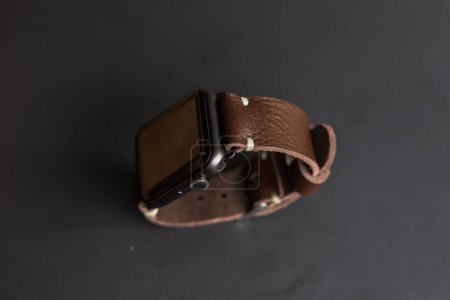 Téléchargez les photos : Bracelet en cuir véritable avec montre intelligente sur fond noir - en image libre de droit