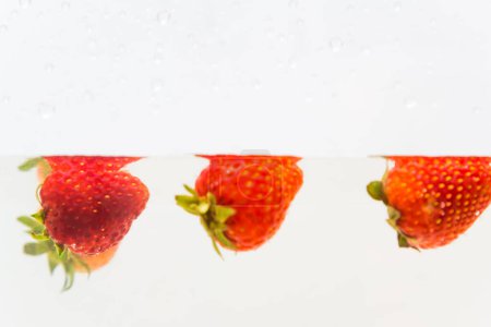 Foto de Fruta fresca de fresa en agua clara sobre fondo blanco - Imagen libre de derechos