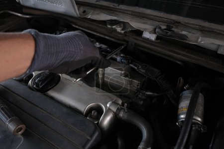 Téléchargez les photos : Mécanicien main réparation allumage sur l'industrie du transport de moteur de voiture - en image libre de droit