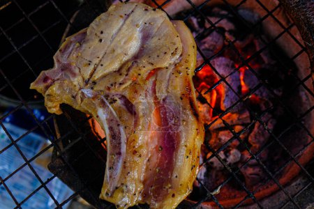 Foto de Filete de cerdo colocado en la parrilla de barbacoa sobre llama ardiente - Imagen libre de derechos