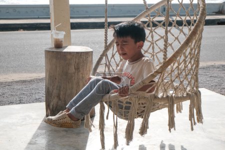 Foto de Asiático chico disfrutando mintiendo en playa hamaca - Imagen libre de derechos