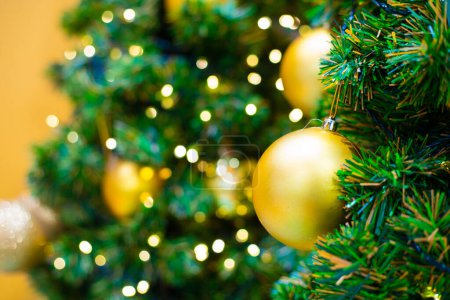 Téléchargez les photos : Boule de Noël dorée sur branche de pin feuille verte fond bokeh flou joyeux noël - en image libre de droit
