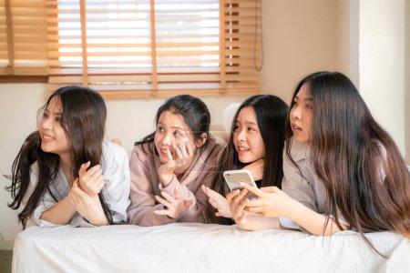 Téléchargez les photos : Belle asiatique femme ami meetin sur lit blanc utiliser smartphone ensemble heureux amitié temps - en image libre de droit