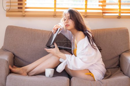 Photo for Business asian woman lying on sofa use laptop computer in cozy house morning wake up work from anywhere - Royalty Free Image
