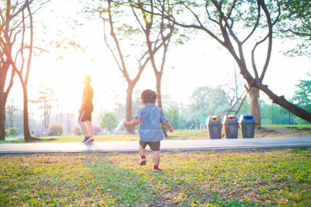 Téléchargez les photos : Heureux joyeux tout-petit asiatique 2 année garçon jouer dans ville public parc coucher de soleil chaud lumière extérieur activité - en image libre de droit