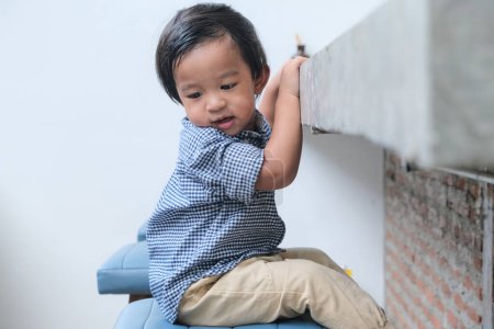Foto de Adorable 2 año asiático chico jugando silla en café restaurante - Imagen libre de derechos