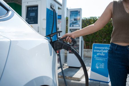 Foto de Mujer de negocios inteligente usa la carga de coche en cada estación de energía sostenible - Imagen libre de derechos