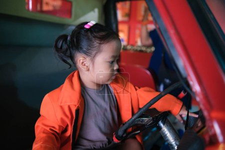 Téléchargez les photos : Petite adorable fille asiatique jouer camion de pompier porter feu homme carrière imagination de l'enfant - en image libre de droit