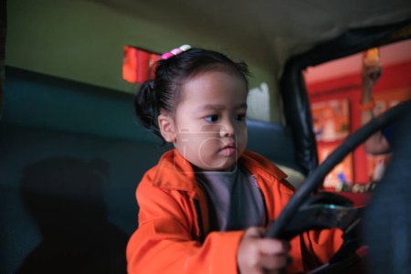 Foto de Poco adorable asiático chica jugar fuego camión desgaste fuego hombre carrera imaginación de niño - Imagen libre de derechos
