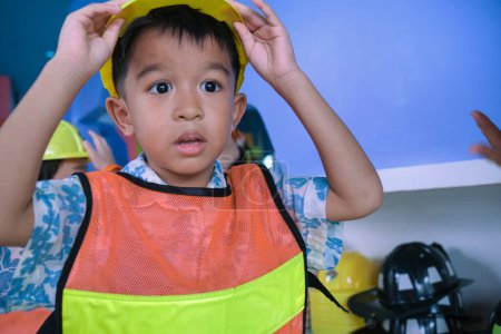 Téléchargez les photos : Jardin d'enfants asiatique garçon jouer ingénieur construction mécanique homme carrière bloc de couleur bâtiment aire de jeux intérieure - en image libre de droit