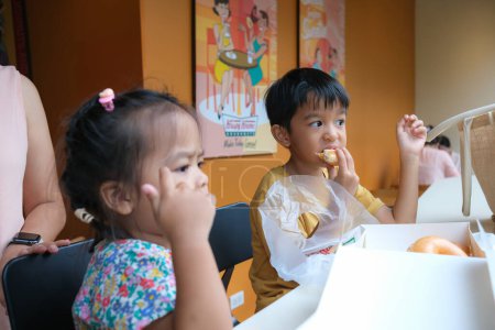 Foto de Hermano y hermana niños comen donas dulces en el supermercado niño feliz - Imagen libre de derechos