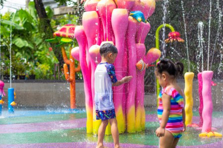 Téléchargez les photos : Heureux enfant garçon et fille profiter de l'eau éclaboussure parc aquatique en plein air vacances d'été - en image libre de droit