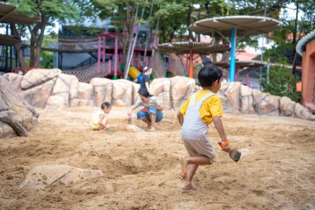 Téléchargez les photos : Asiatique enfant garçon 5 ans profiter de jouer bac à sable en plein air avoir du plaisir sur aire de jeux dans le bac à sable. Activités créatives de jardin d'enfants en plein air - en image libre de droit