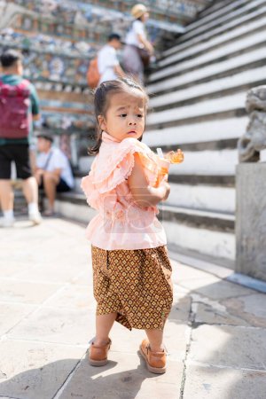 Photo for Adorable kindergarten girl wear Thai style costume travel in Wat Arun sightseeing travel in Bangkok Thailand - Royalty Free Image