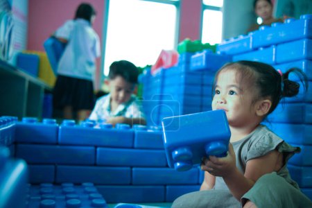 Foto de Adorable niña disfrutando con la construcción de bloques de juguete patio interior feliz niña preescolar - Imagen libre de derechos