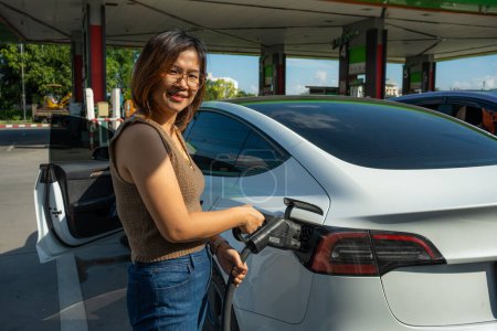 Téléchargez les photos : Femme d'affaires intelligente utiliser ev charge de voiture dans la station ev énergie durable - en image libre de droit