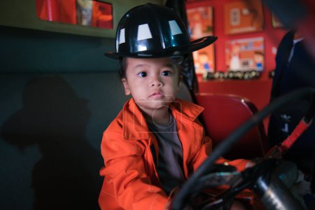 Photo for Little adorable asian girl play with fire truck wear fire man costume - Royalty Free Image