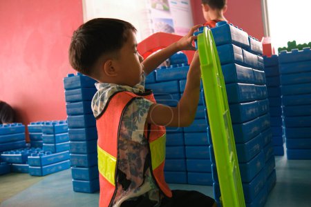 Photo for Kindergarten asian boy play engineer mechanical building man career color block building indoor playground - Royalty Free Image