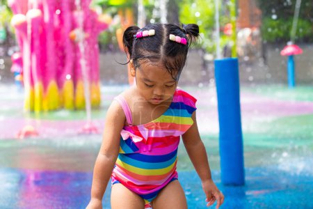Foto de Feliz niño y niña disfrutando de salpicaduras de agua al aire libre parque acuático vacaciones de verano - Imagen libre de derechos