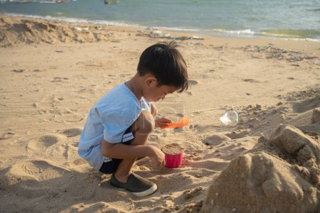 Photo for 5 year kindergarten boy play on sandy beach with colorful toy city beach summer vacation - Royalty Free Image