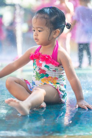 Téléchargez les photos : Belle asiatique tout-petit fille appréciant jouer en plein air ville parc aquatique vacances d'été - en image libre de droit