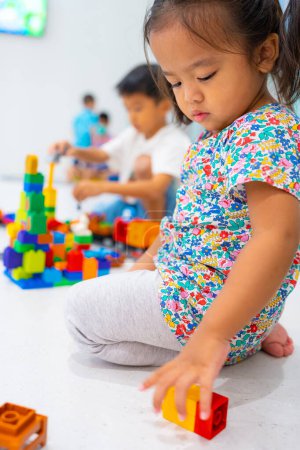 Foto de Niño pequeño 2 años chica disfrutando construir juguete bloque feliz chica aprendiendo educación interior aula - Imagen libre de derechos