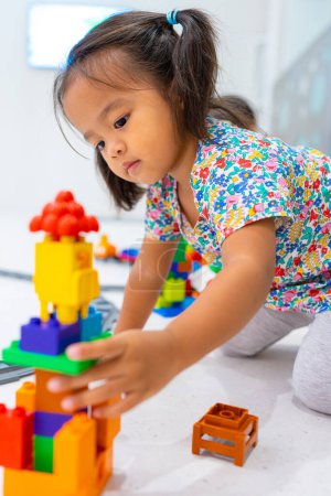 Photo for Toddler 2 year girl enjoying build toy block happy girl learnning education indoor classroom - Royalty Free Image