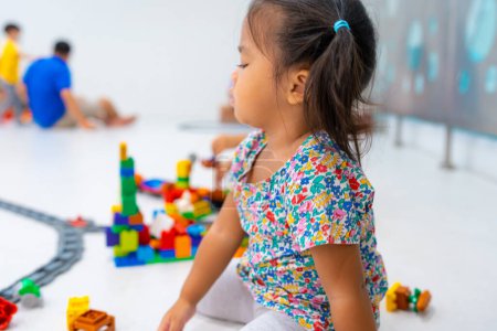 Téléchargez les photos : Tout-petit fille de 2 ans appréciant construire bloc jouet fille heureuse apprenant l'éducation salle de classe - en image libre de droit