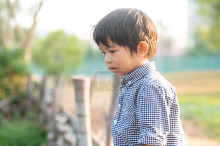 Téléchargez les photos : Asiatique préscolaire garçon profiter de plein air loisirs ville parc à la lumière du coucher du soleil - en image libre de droit